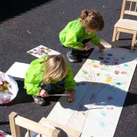 Barn som ritar ett stort träd på ett lång papper